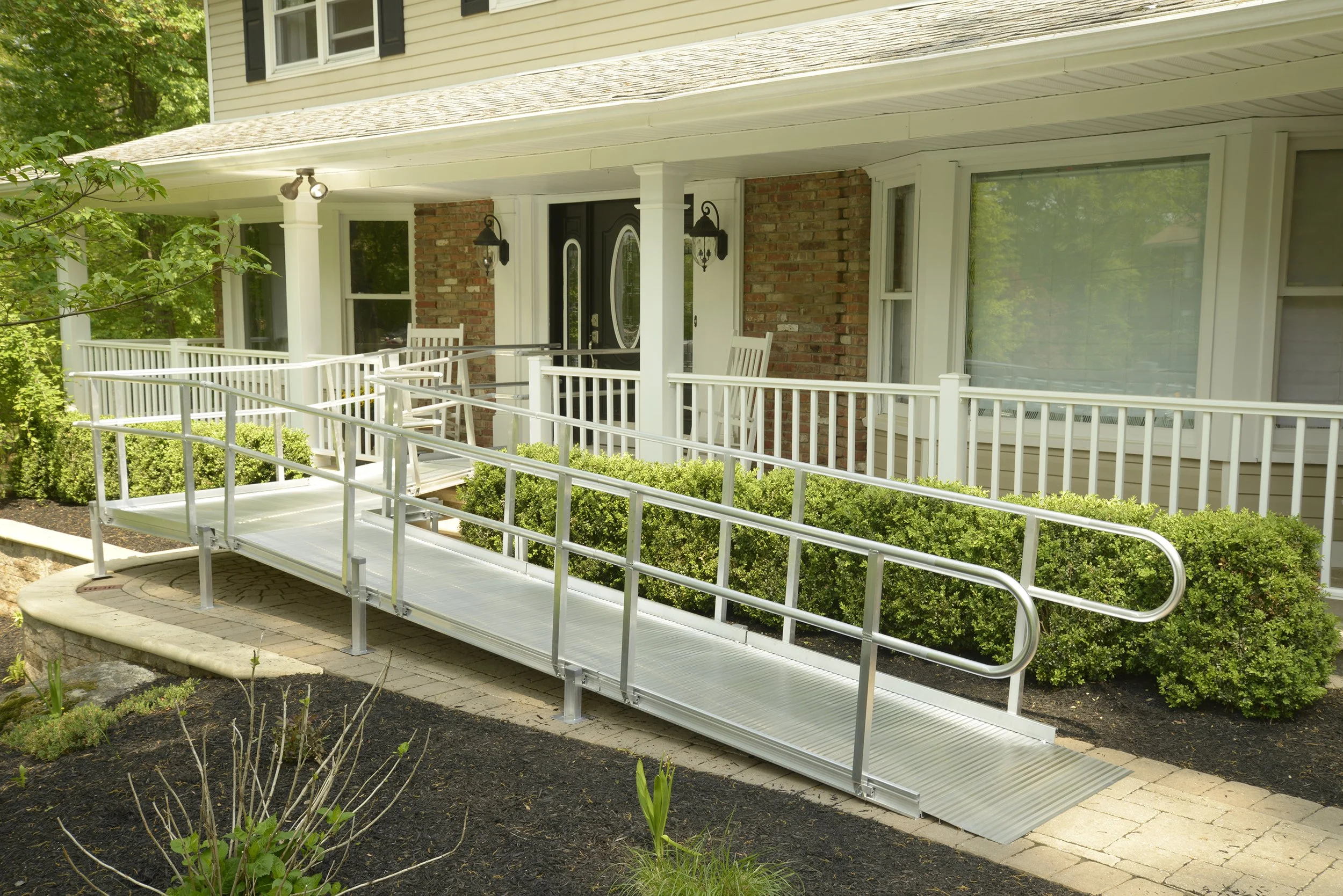 Aluminum access ramp with handrails leading to a home’s covered front porch